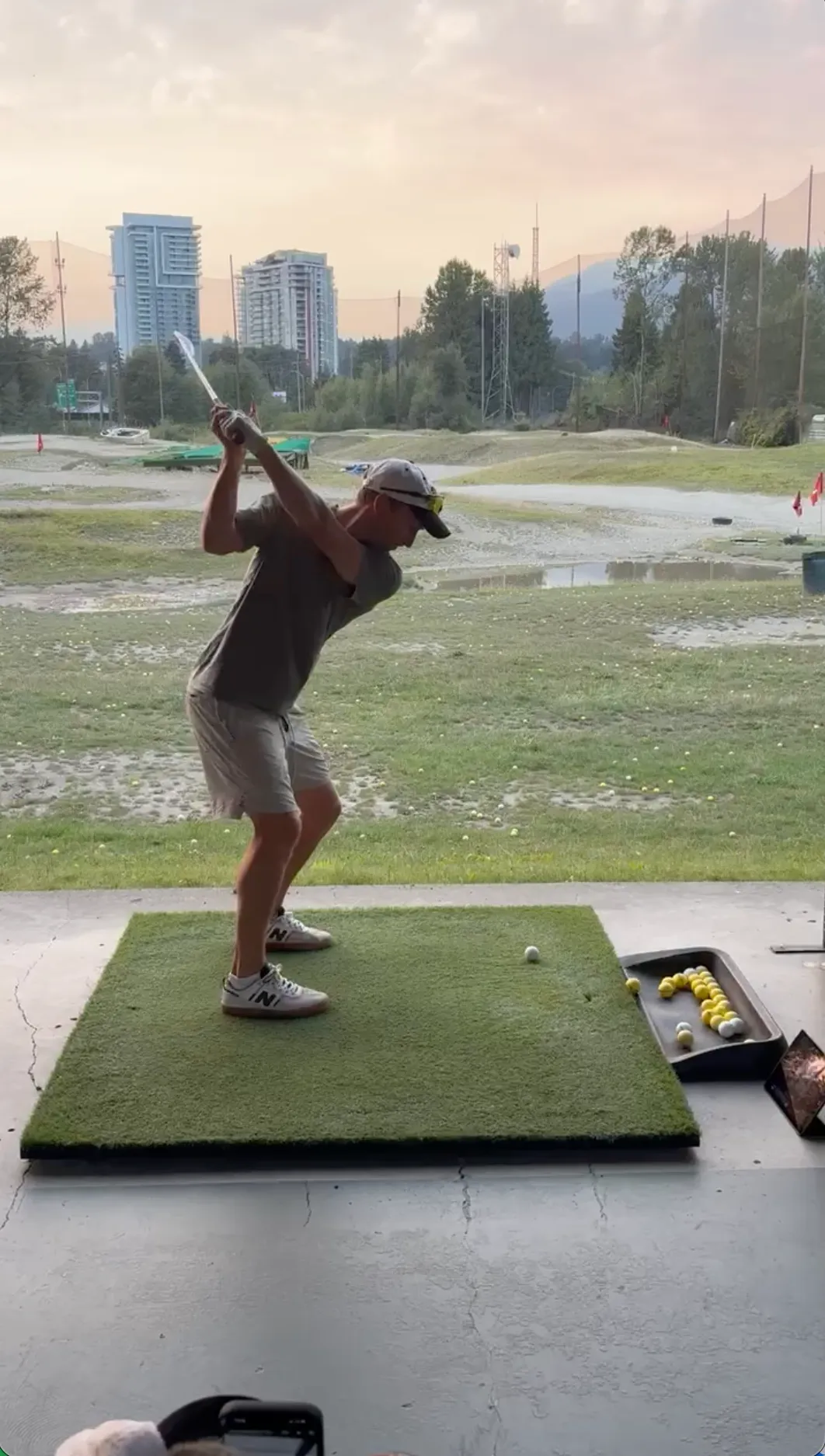 A golfer at the top of his backswing on the driving range